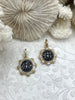 Image of May include: Two gold and silver bee charms with black enamel. The bee charms are round and have a detailed design. The charms are on a white background with a floral pattern.